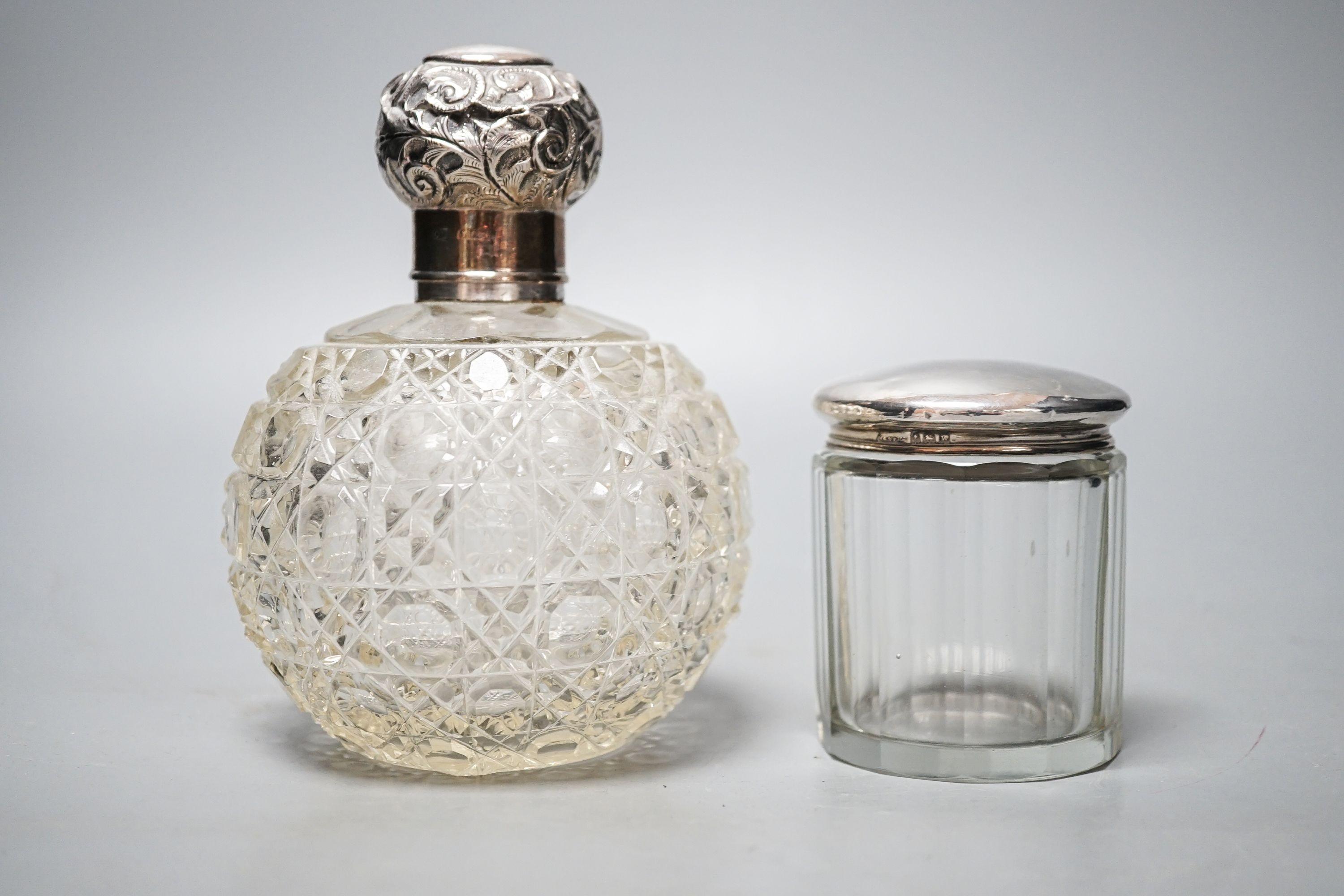 An Edwardian silver topped cut glass globular scent bottle, Birmingham, 1906, 15.3cm and a silver topped toilet bottle.